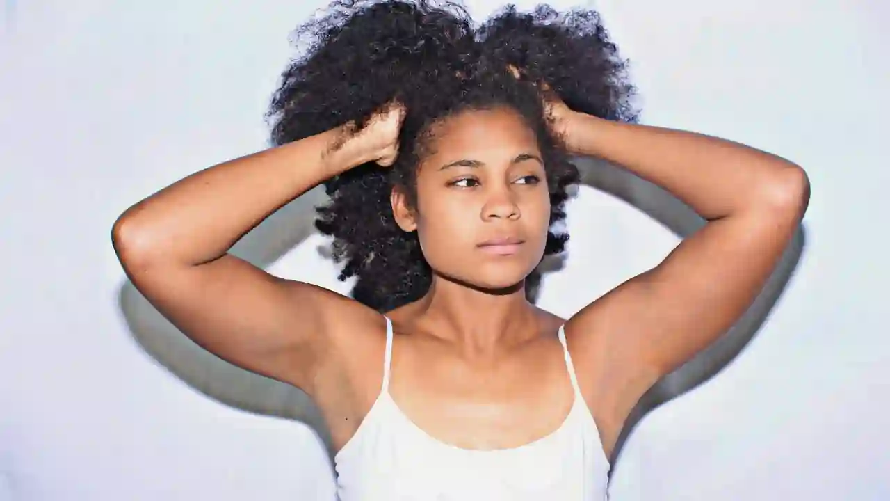 A woman showcasing the results of healthy hair, skin, and nail vitamin supplementation