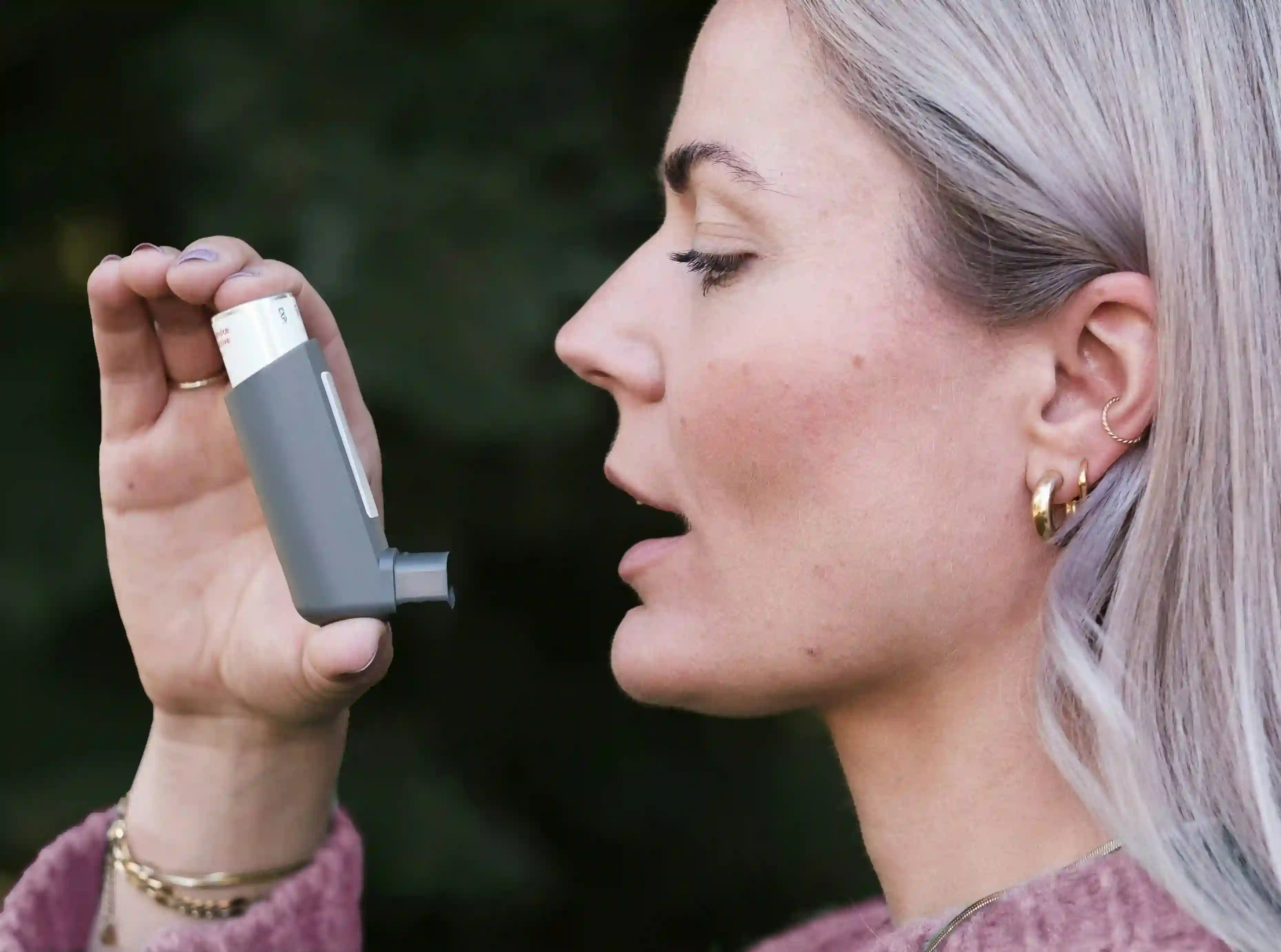 A picture showing an asthmatic woman using an inhaler.